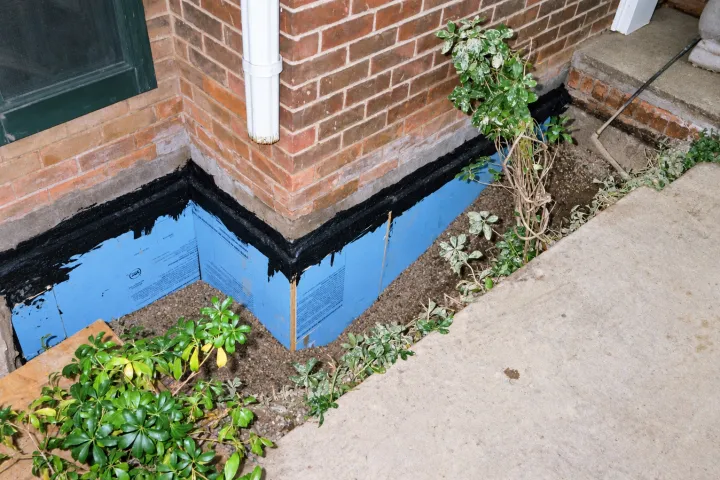 Foundation corner wrapped in waterproof membrane, ready for backfill